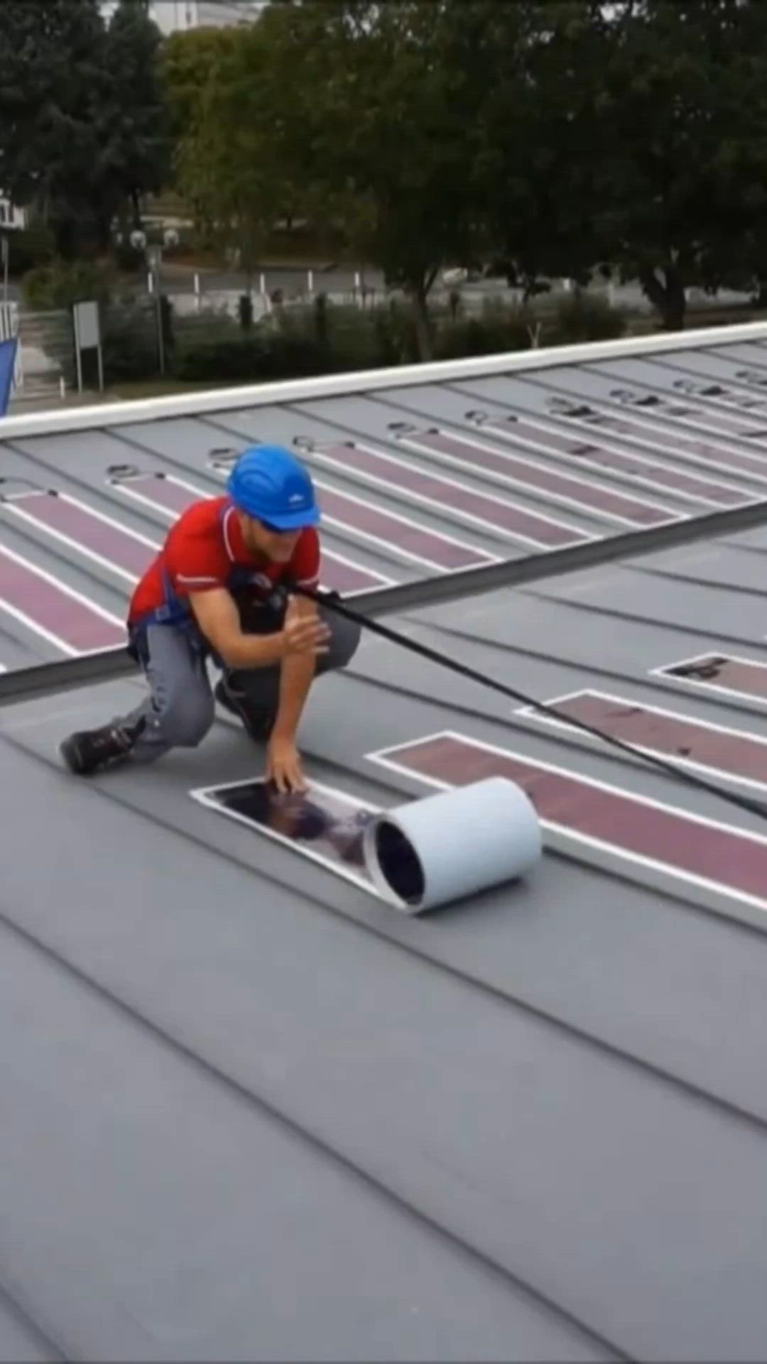 This may contain: two men working on the roof of a building with paint rollers in their hands