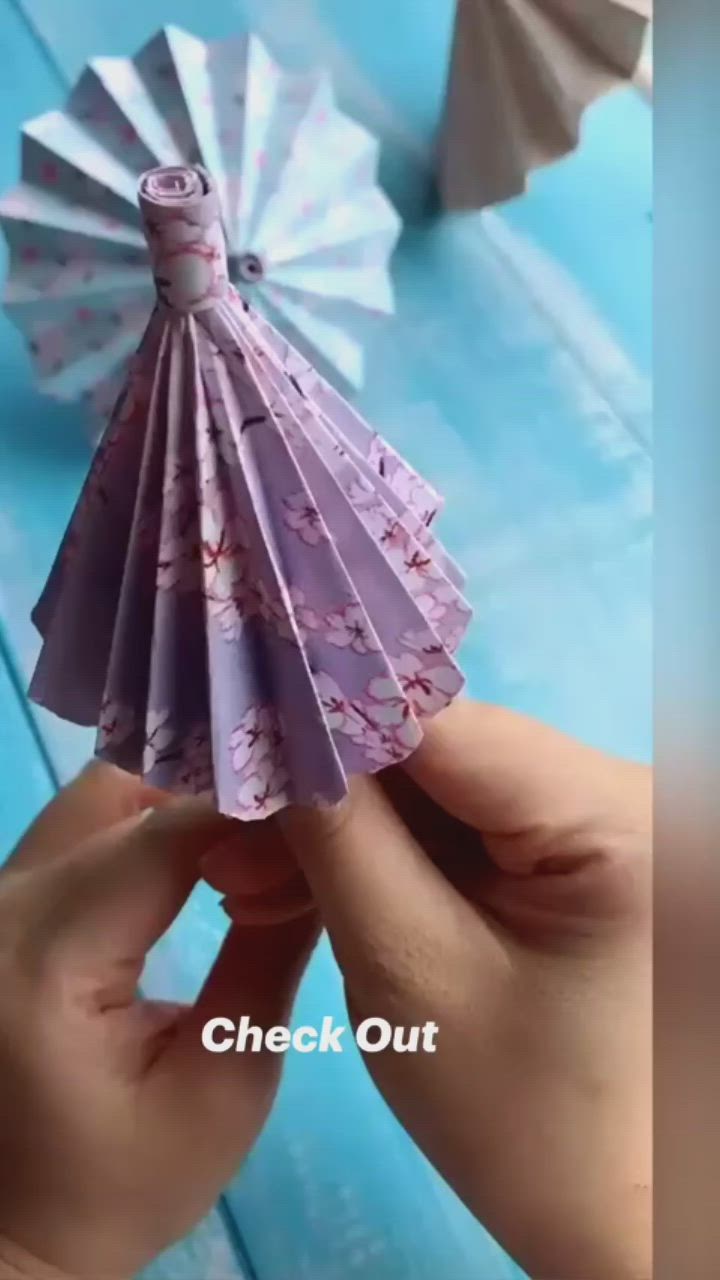 This may contain: someone is holding an origami fan in their hand