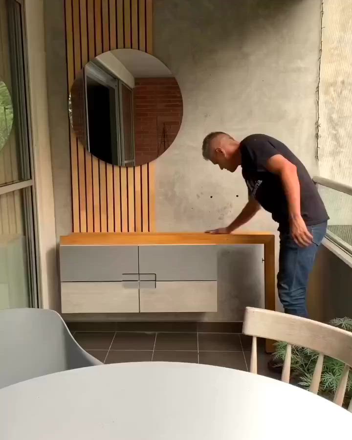 This may contain: a man standing on top of a wooden table next to a white chair and mirror