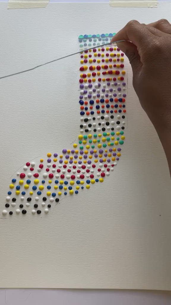 This may contain: a hand is holding a piece of art made out of small colored dots on white paper