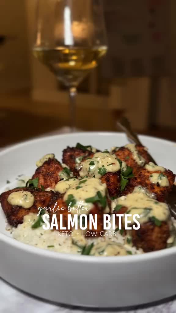 This contains: A platter of mouthwatering creamy garlic butter salmon bites, perfectly cooked and garnished with fresh herbs. A delightful keto seafood treat!