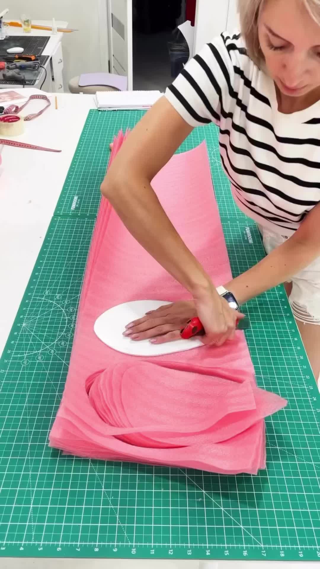 This may contain: a woman is cutting fabric on a table