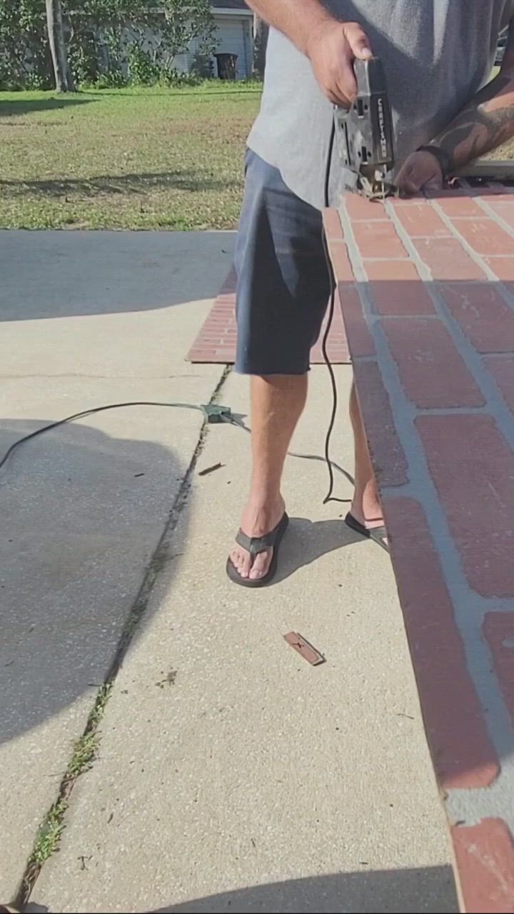 This may contain: a man is using a power drill to fix a brick wall in his driveway area