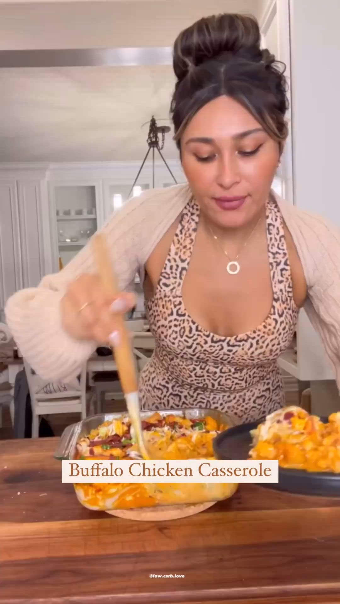 This may contain: a woman is cooking in the kitchen with a wooden table and white walls behind her