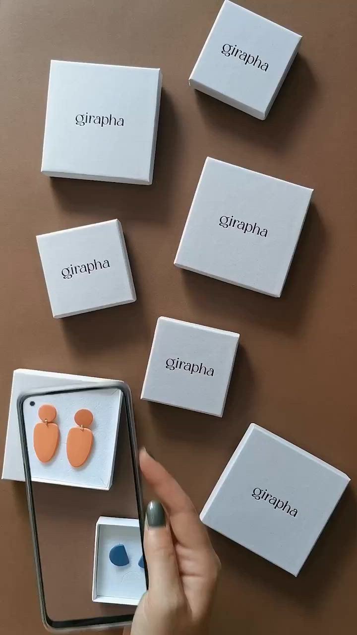 This may contain: a person holding a cell phone in front of several boxes with magnets on them