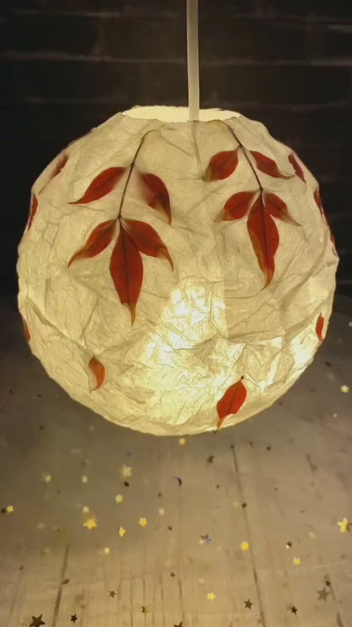 This may contain: a white paper lantern with red leaves on it