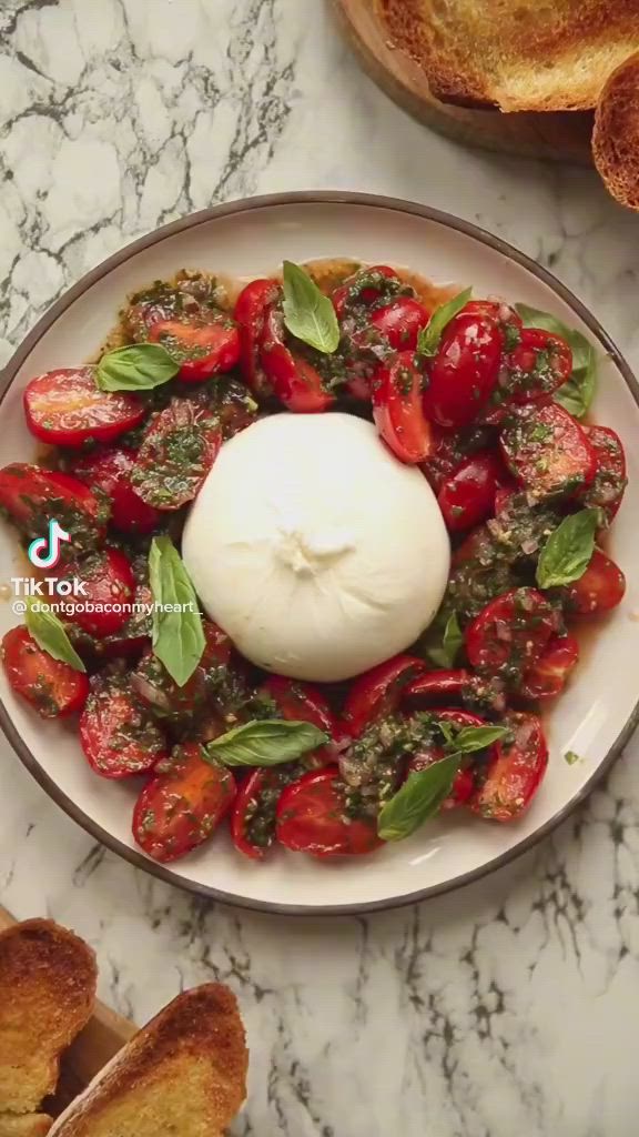 This contains: Tiktok recipe Italian tomato salad with basil and burrata.