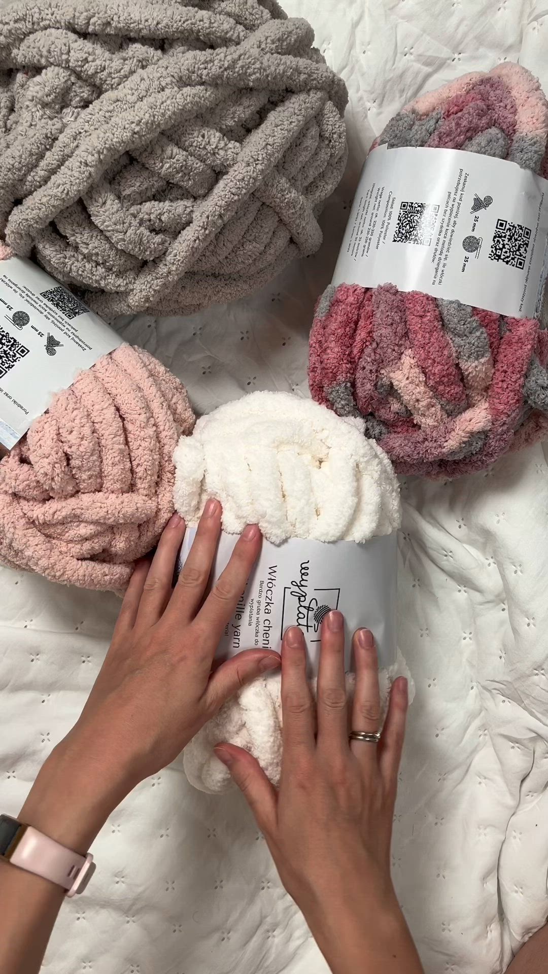 This may contain: two hands are working on some knitted items with one hand reaching for the yarn