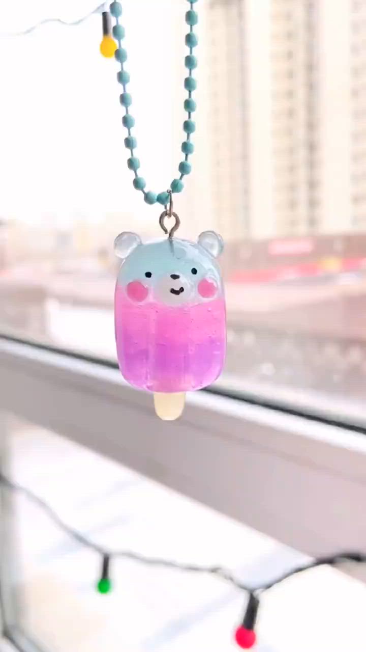 This may contain: a necklace with a bear on it hanging from the side of a window sill