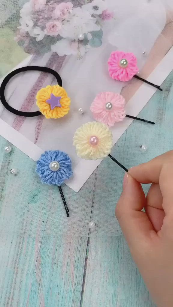 This may contain: three different colored hair clips on top of a wooden table with flowers in the background