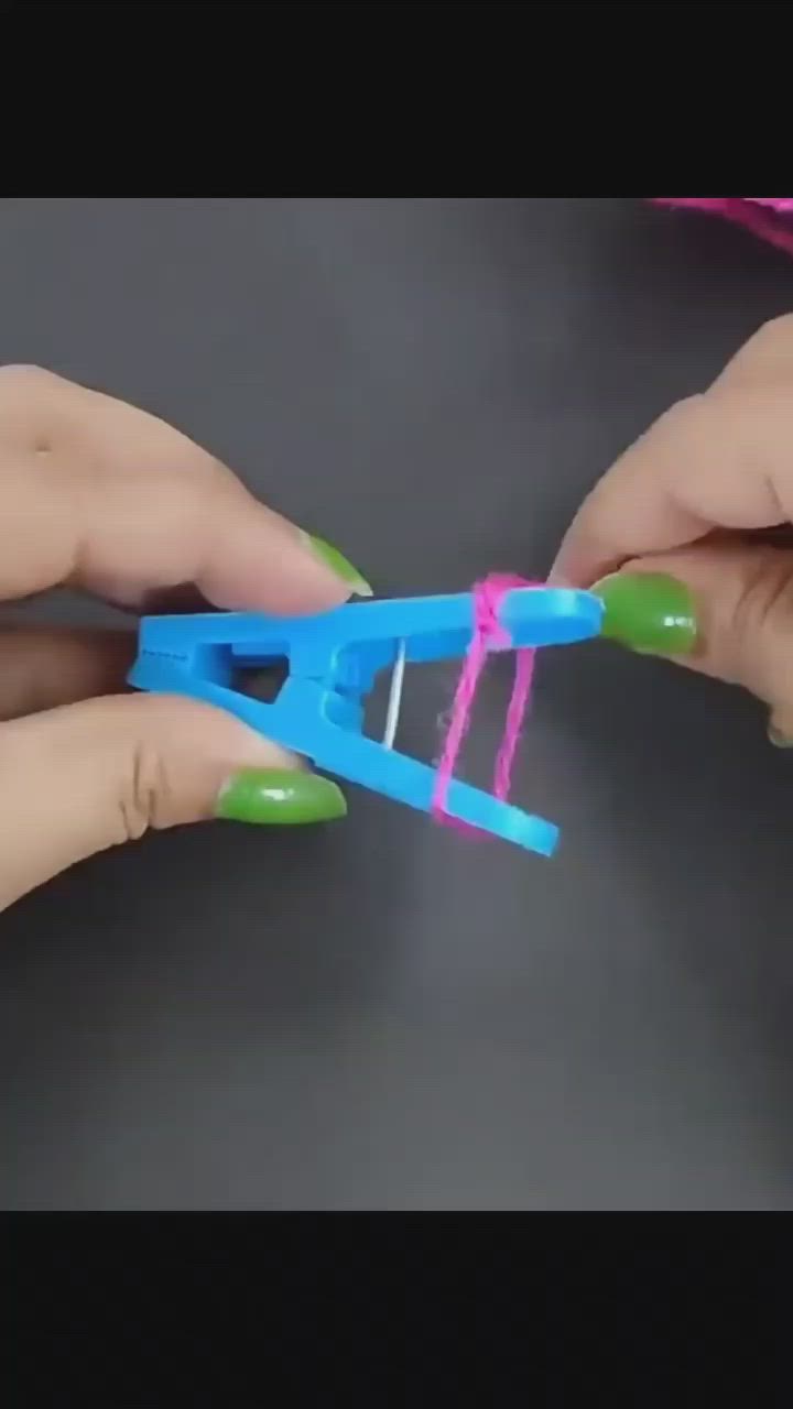 This may contain: two hands are holding scissors with pink and blue string attached to the handle, while another person is using green nail polish on their nails