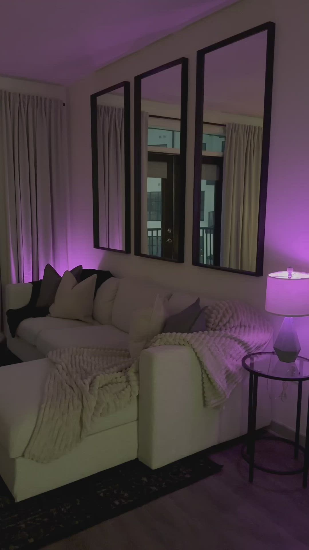 This may contain: a living room filled with white furniture and purple lighting