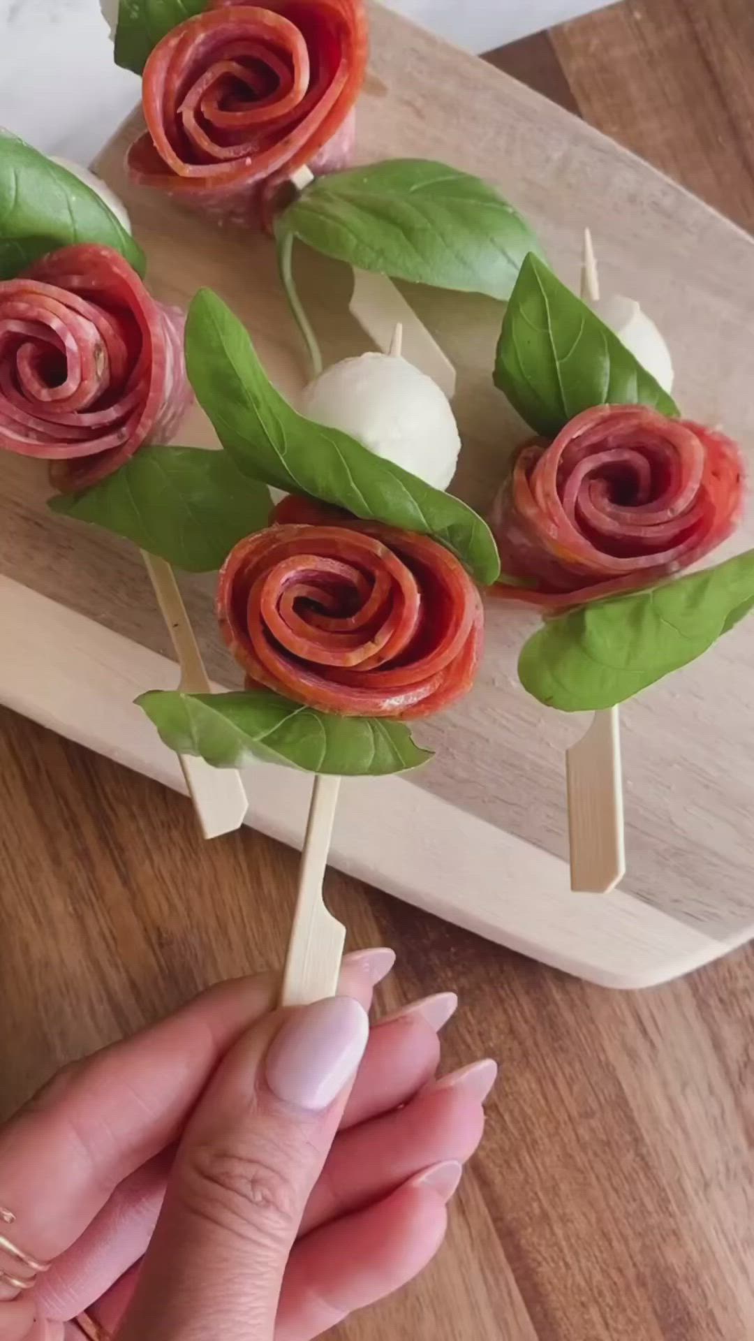 This may contain: a person is holding some food on a stick with leaves and flowers in the middle