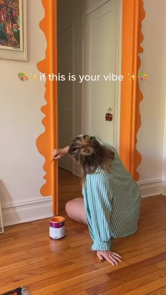 This may contain: a woman kneeling down on the floor in front of a mirror with an orange frame