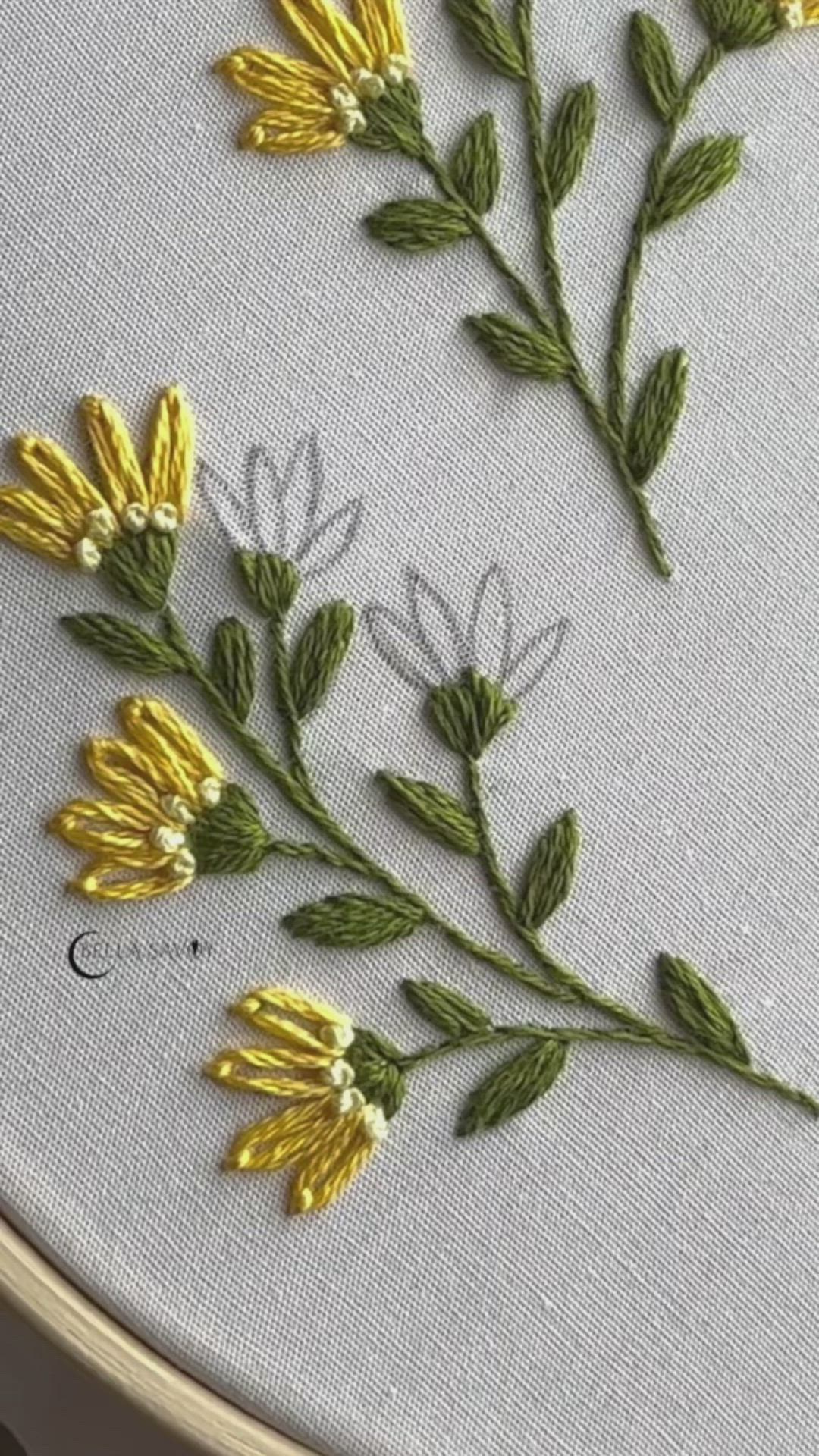 This may contain: some yellow flowers are sitting on a white table cloth and the embroidery has been stitched onto it