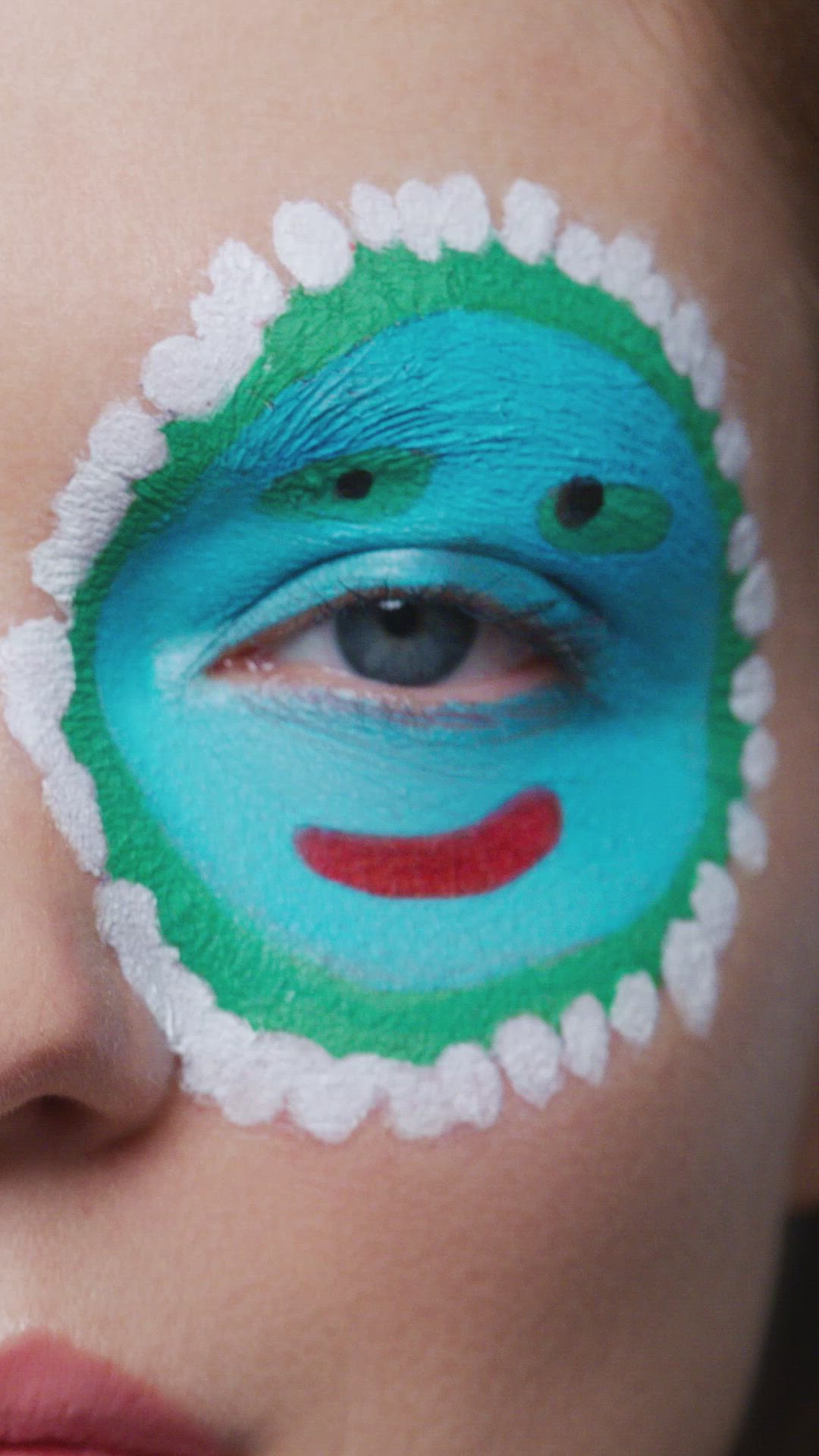 This may contain: a woman with blue and green make up on her face