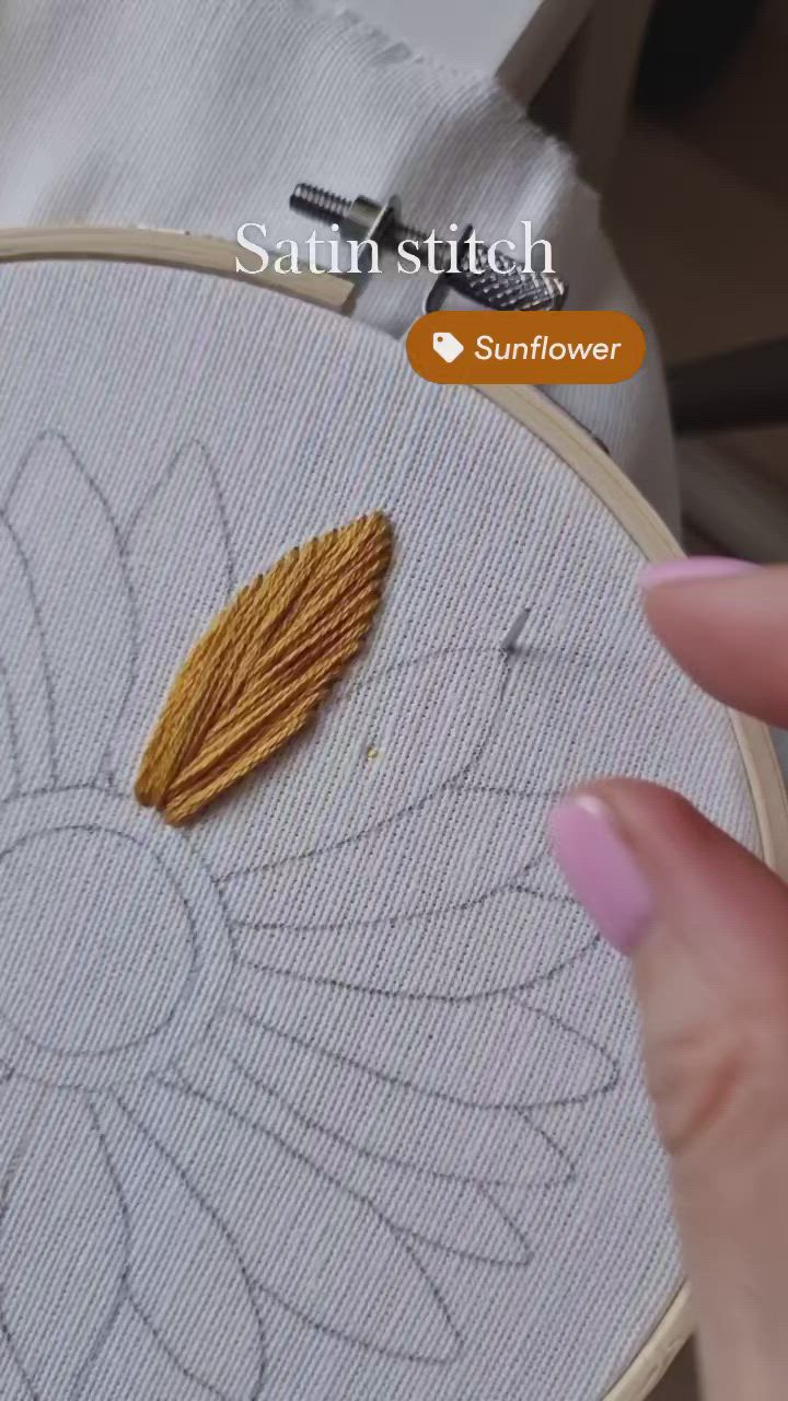 This may contain: a woman's hand holding a needle and thread in front of a flower embroidery pattern