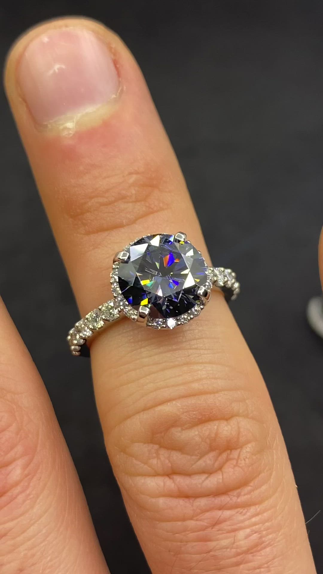 This may contain: a woman's engagement ring with an oval blue diamond surrounded by diamonds on her finger