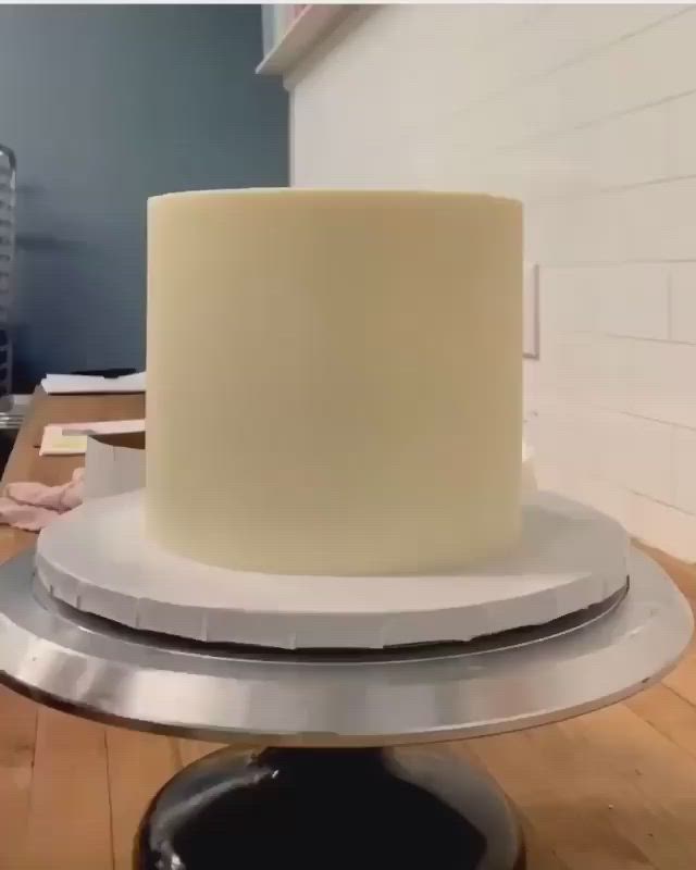 This may contain: a white and gold cake with pink flowers on top