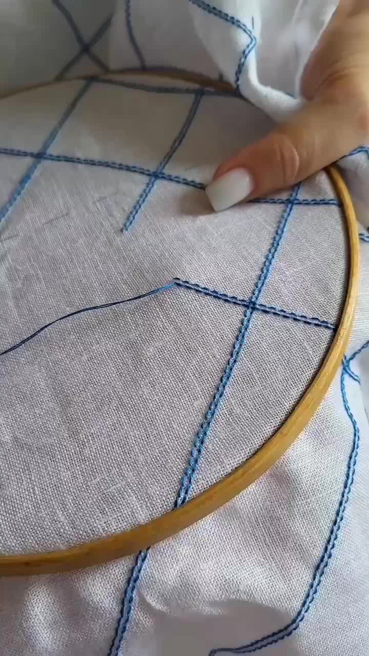 This may contain: someone is stitching on the fabric with a wooden hoop in front of their hand