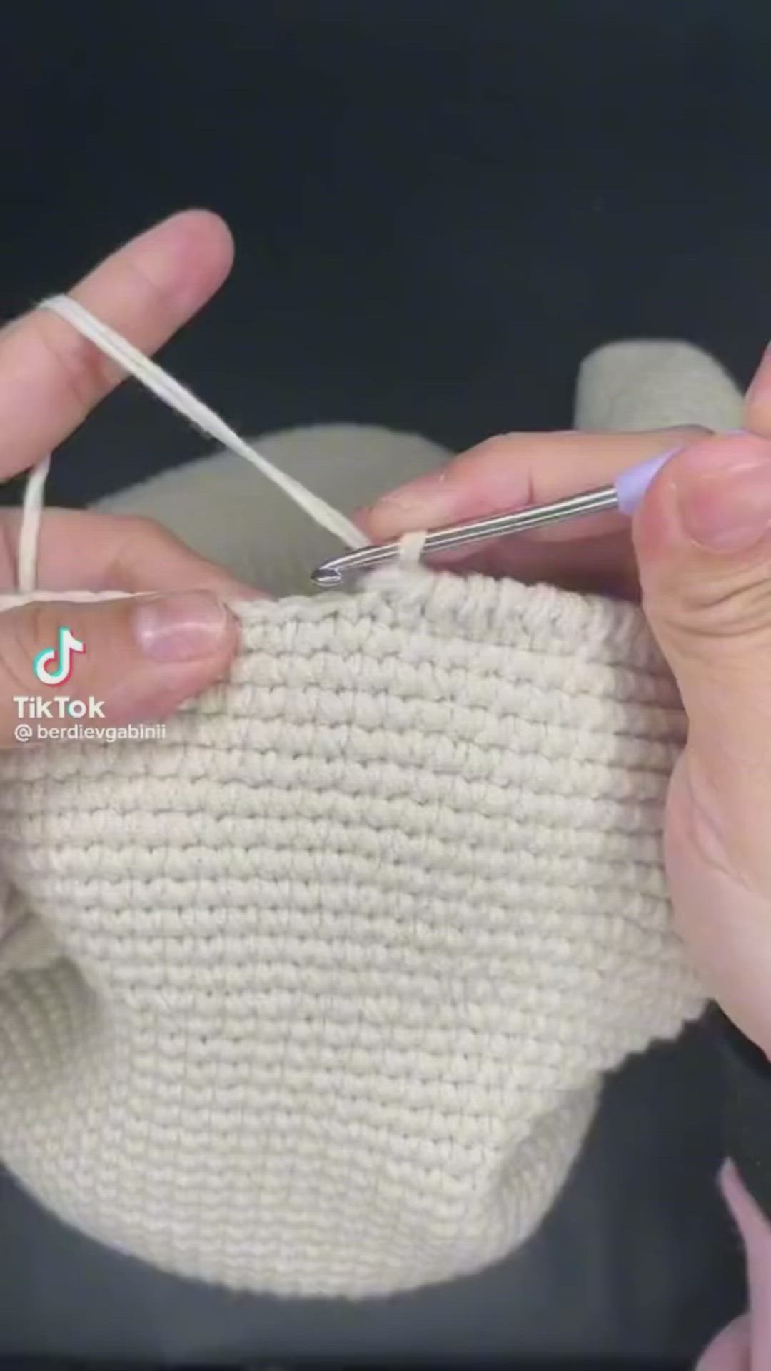 This may contain: two hands are knitting the ends of a white knitted mitt with yarn in it