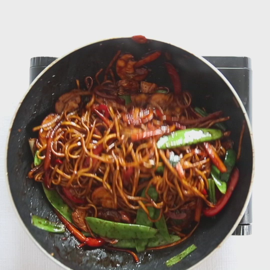 This may contain: a wok filled with stir fry vegetables and sesame seeds