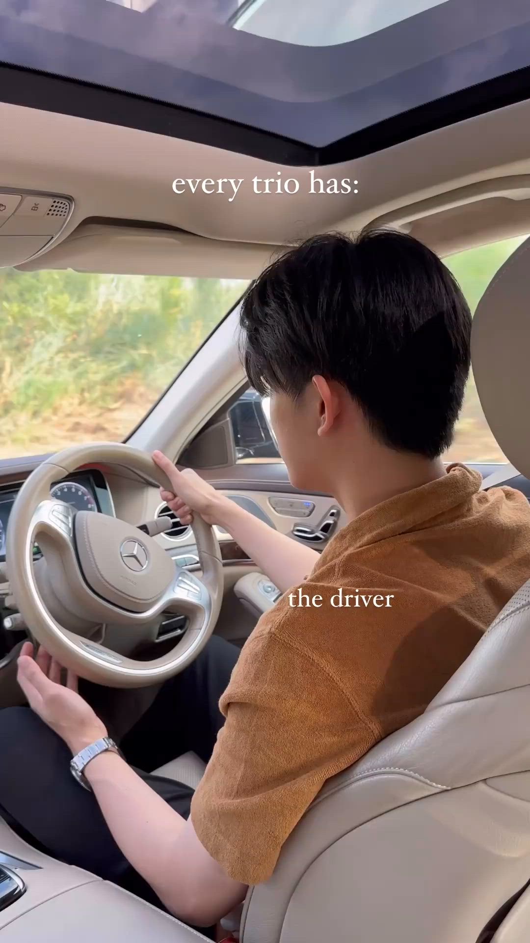 This may contain: a man sitting in the driver's seat of a car with his hand on the steering wheel