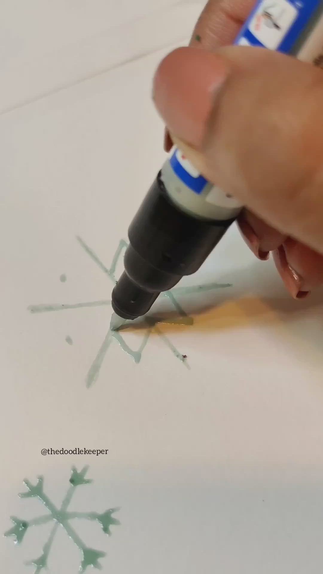 This may contain: someone is drawing a snowflake on paper with a marker and pen in their hand