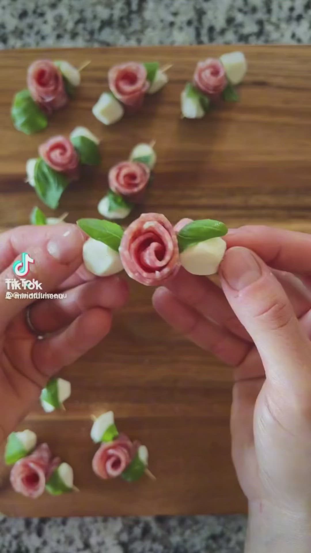 This may contain: a person is cutting up some food on a wooden board with pink flowers and green leaves