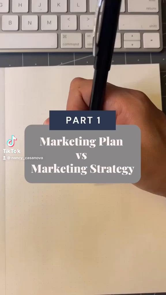 This may contain: a hand holding a pen over a paper with the words marketing plan versus marketing strategy