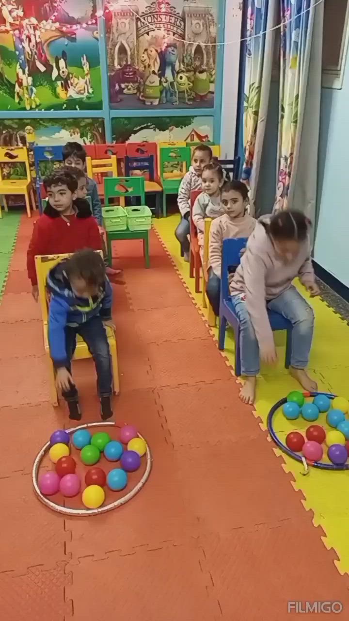 This may contain: children sitting in chairs with balls on the floor and one child standing up behind them