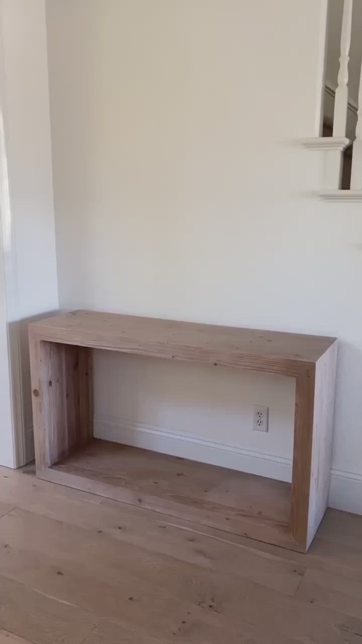 This may contain: a wooden bench sitting on top of a hard wood floor next to a white wall