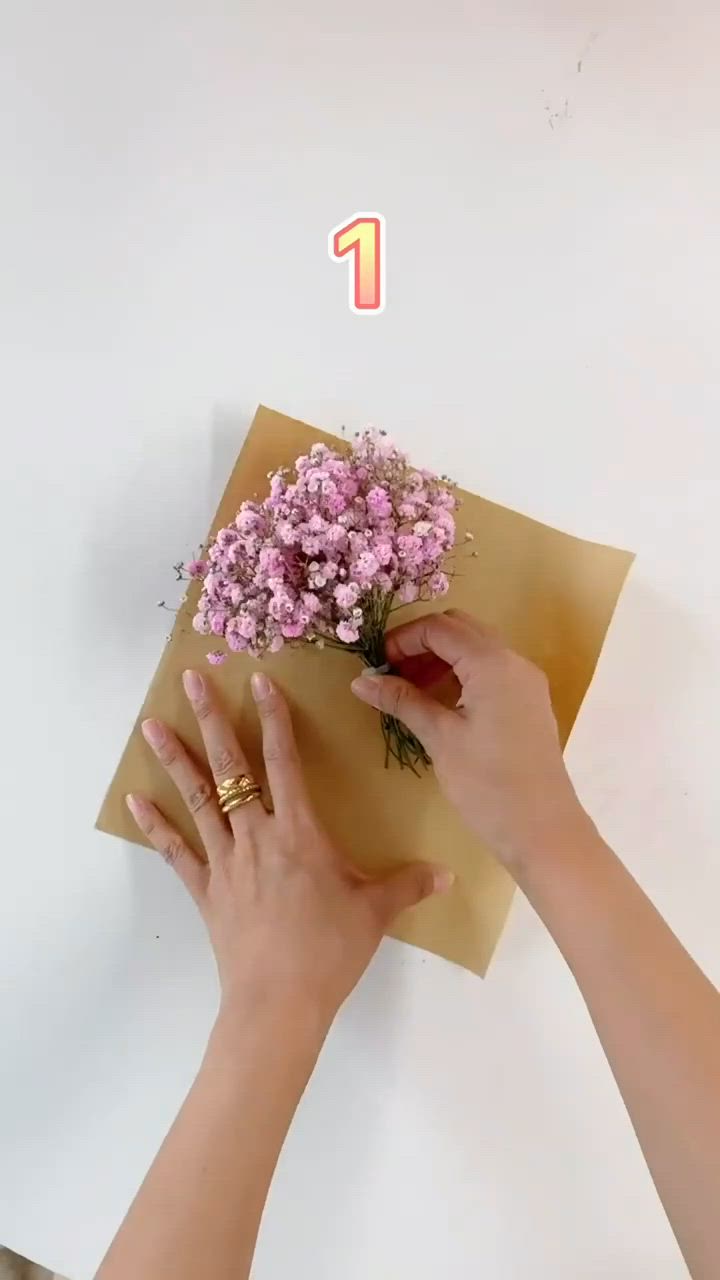 This may contain: two hands holding flowers in front of an envelope with the number one on it,