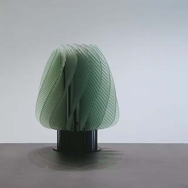 This may contain: a green sculpture sitting on top of a black table next to a white wall and floor