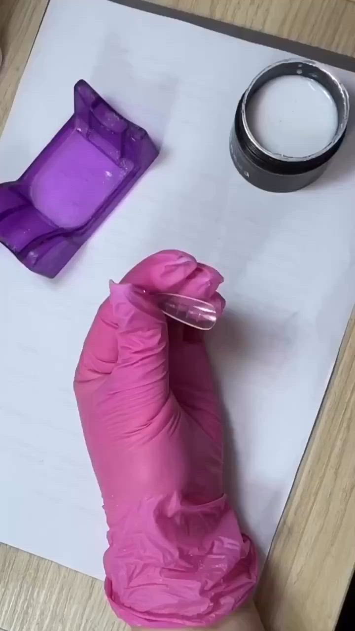 This may contain: a person in pink gloves cutting paper with scissors and other items on the table next to them