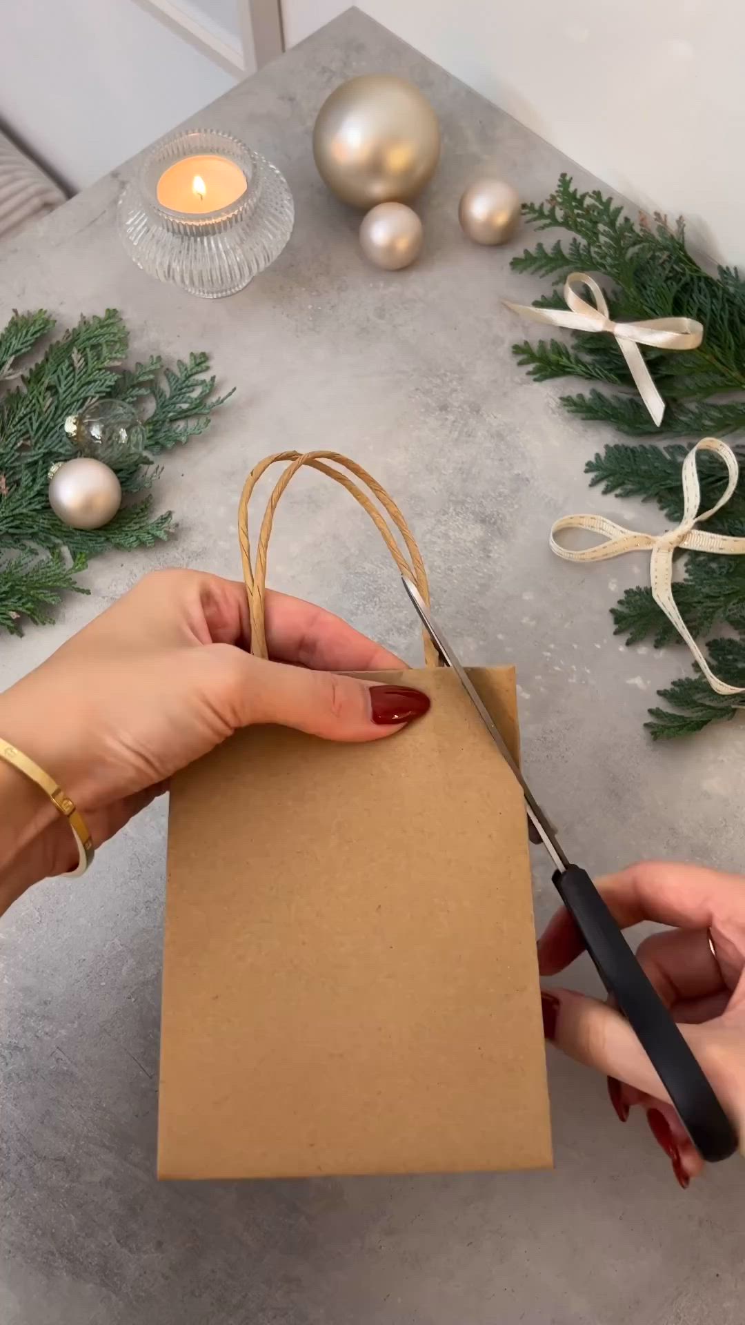 This may contain: a person cutting paper with scissors on top of a table next to christmas decorations and candles