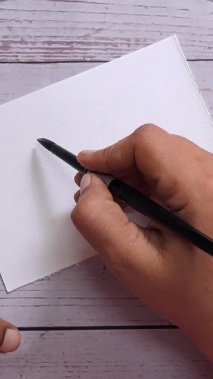 This may contain: a person is holding a paintbrush and drawing on paper with watercolor pencils