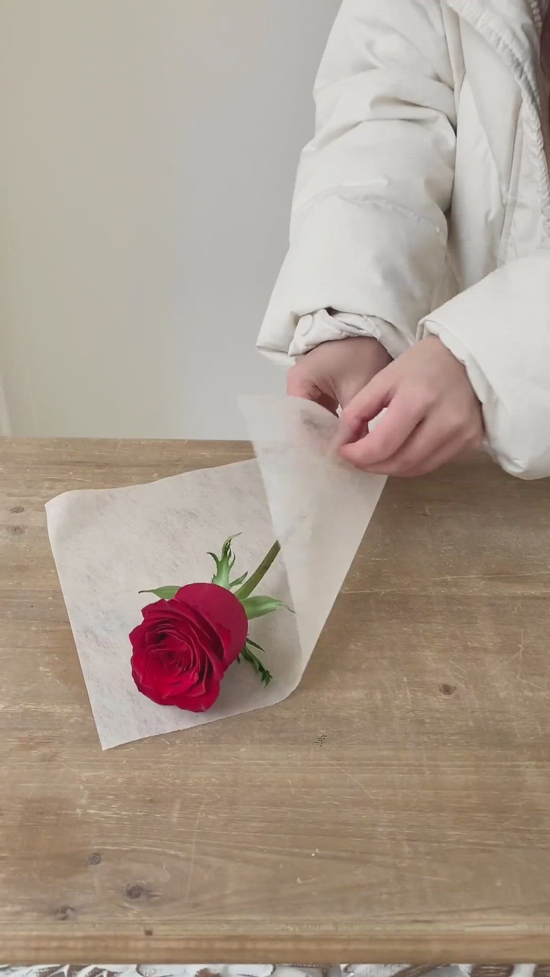 This may contain: a person holding a rose on top of a piece of paper next to a napkin