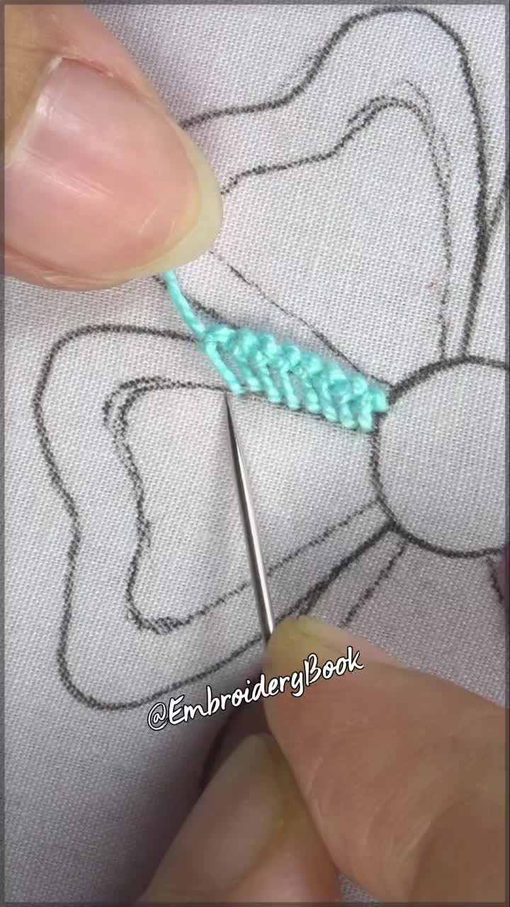 This may contain: someone is stitching something on the fabric with scissors and thread in front of them