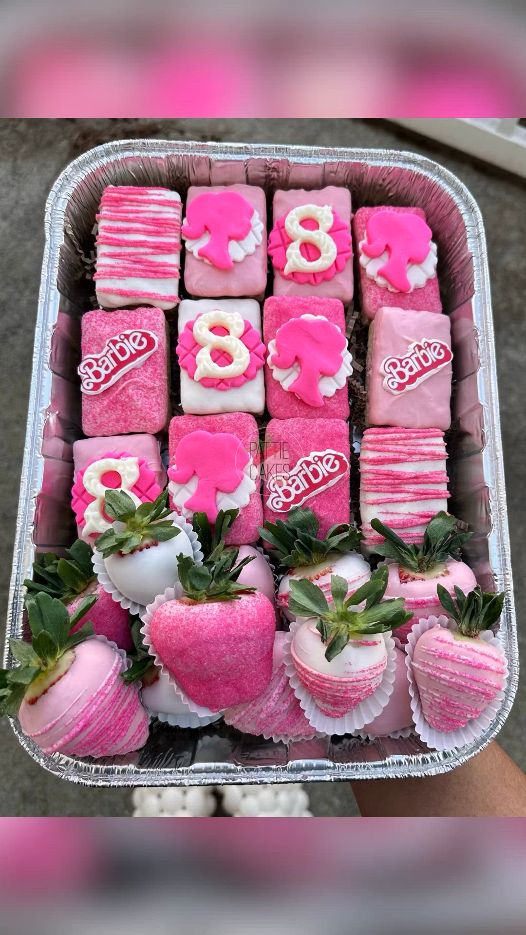 This may contain: a tray filled with lots of pink and white treats