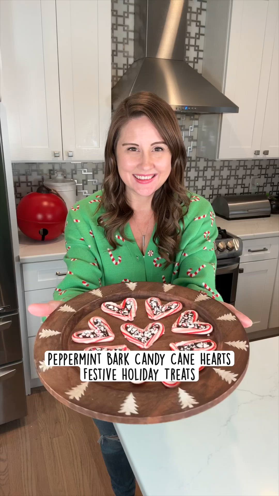 This may contain: a woman holding up a plate with cookies on it that says peppermint bark candy cane hearts festive holiday treats