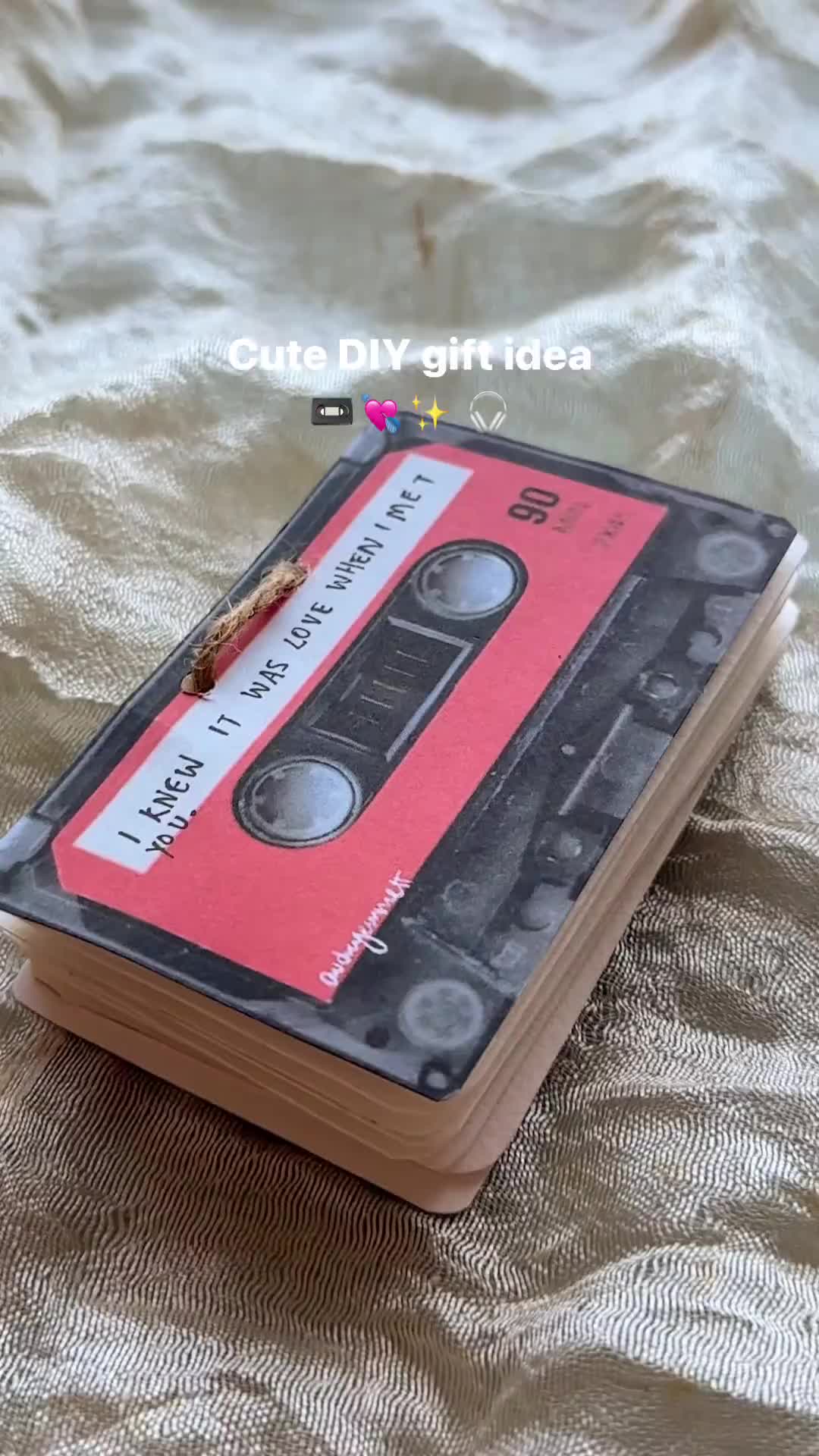 This may contain: an old book with a cassette on it sitting on a bed covered in gold fabric