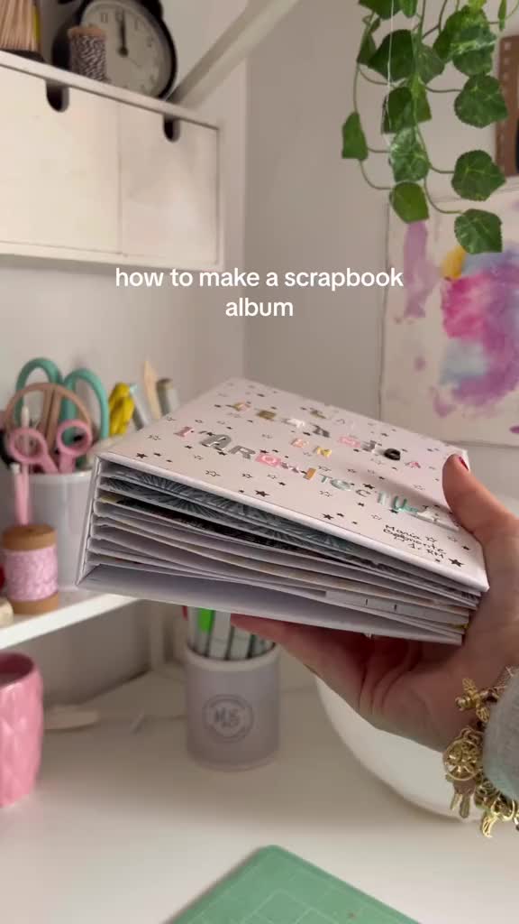 This may contain: a person holding a stack of books in their hand with the words how to make a scrapbook album