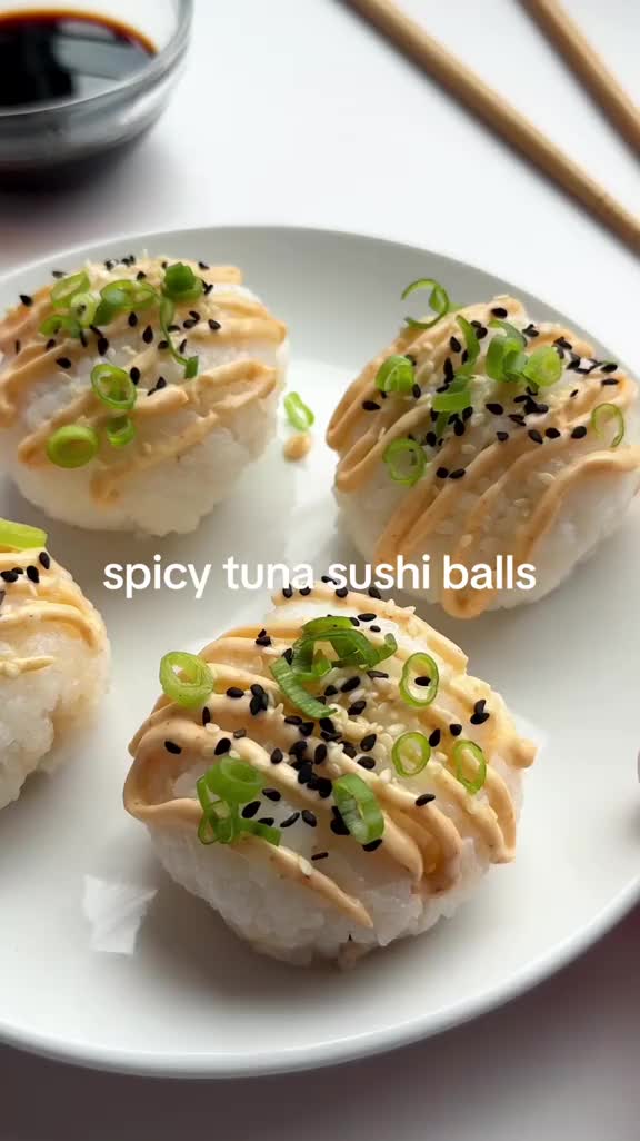 This may contain: four sushi balls on a white plate with chopsticks next to the dish