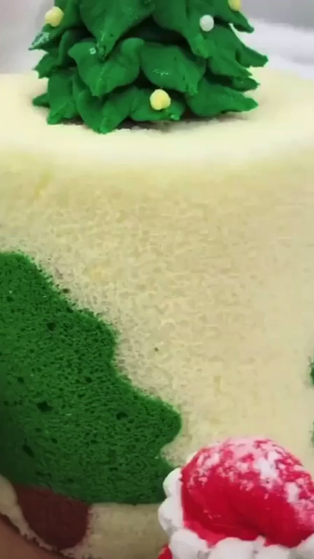 This may contain: a white cake with green frosting and a small christmas tree on it's top