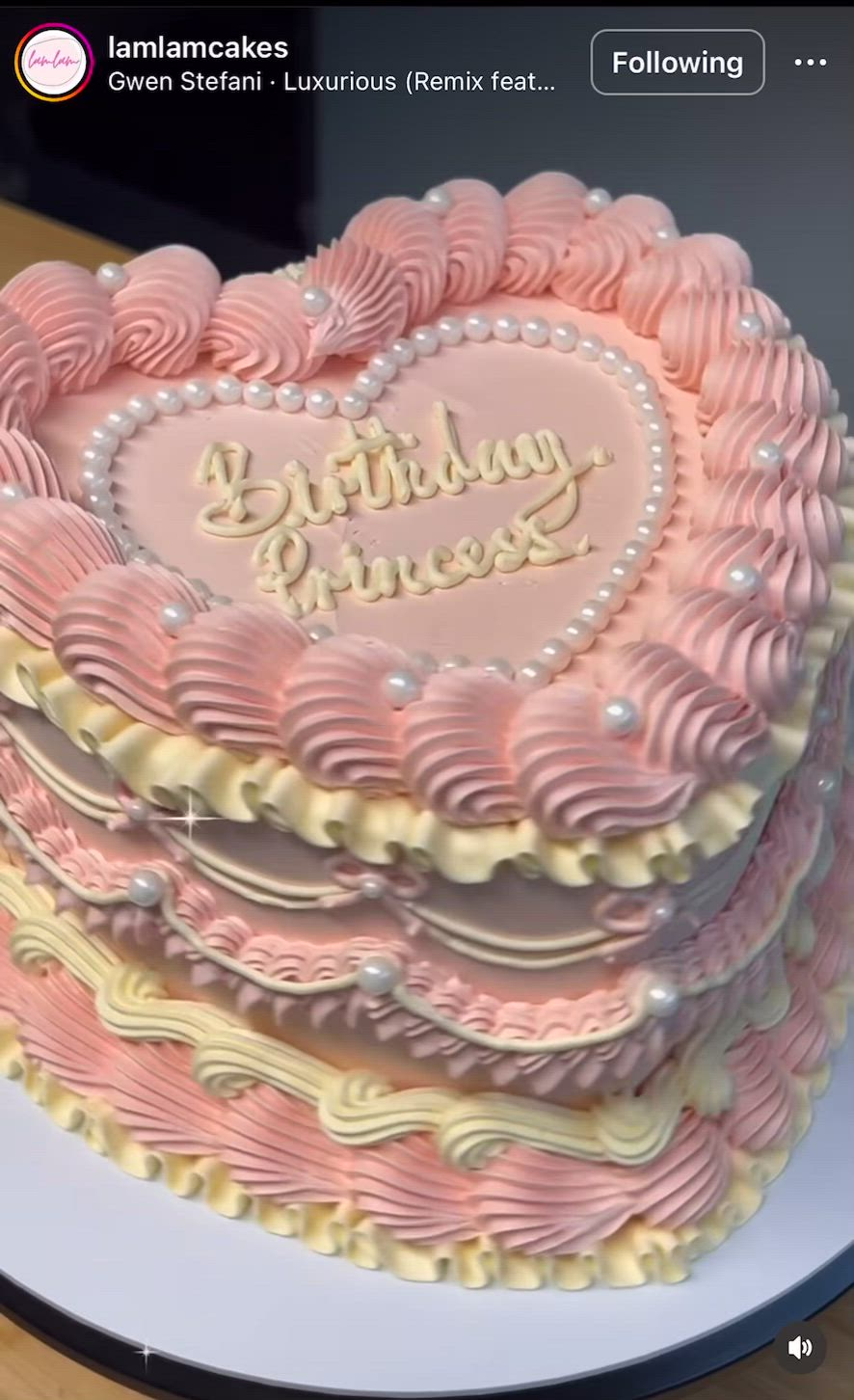 This may contain: a heart shaped birthday cake sitting on top of a white plate with pink frosting