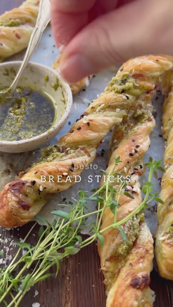 This may contain: bread sticks with pesto on them and dipping sauce