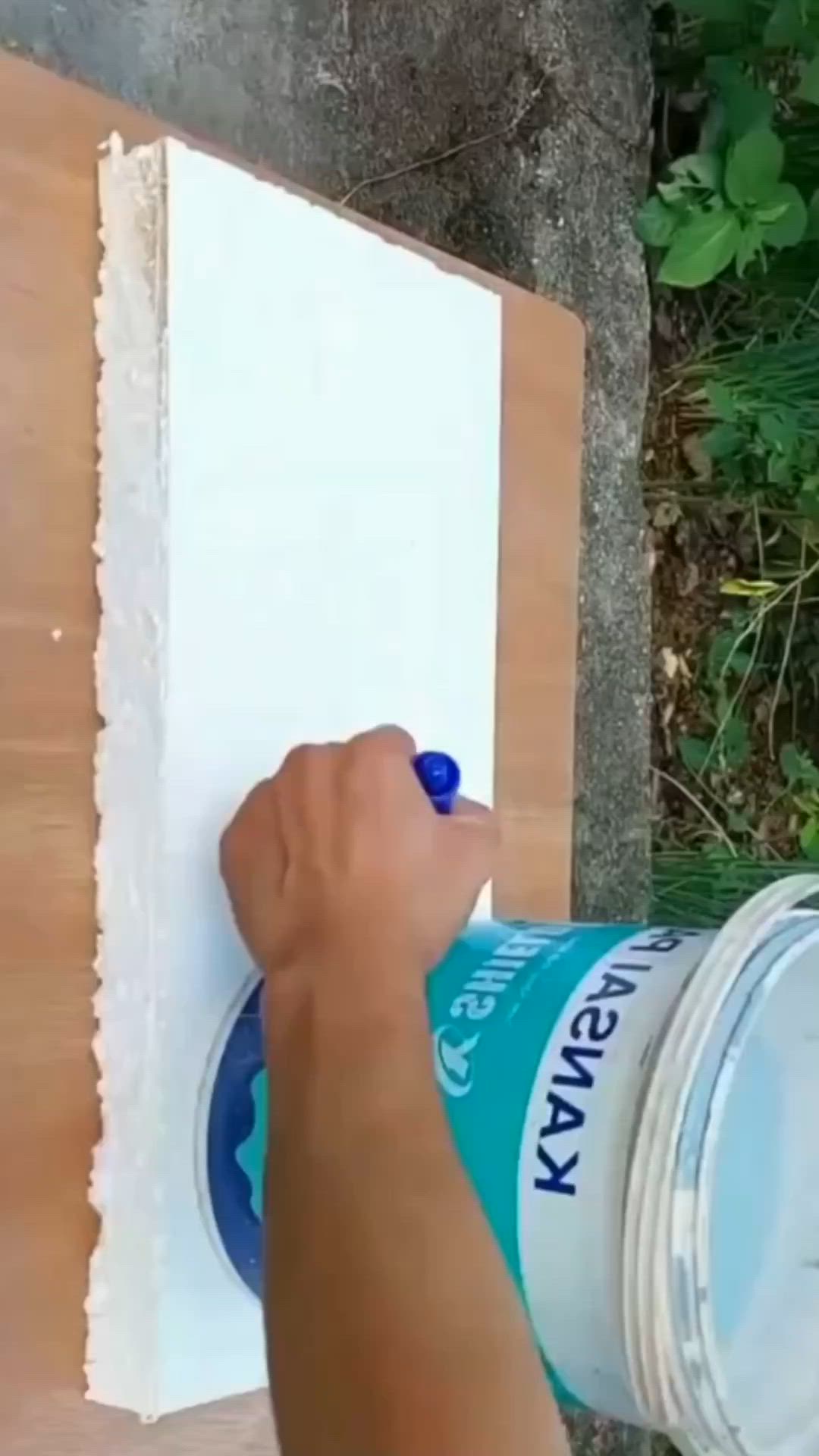 This may contain: a person is using a paint can to paint a piece of wood on the wall