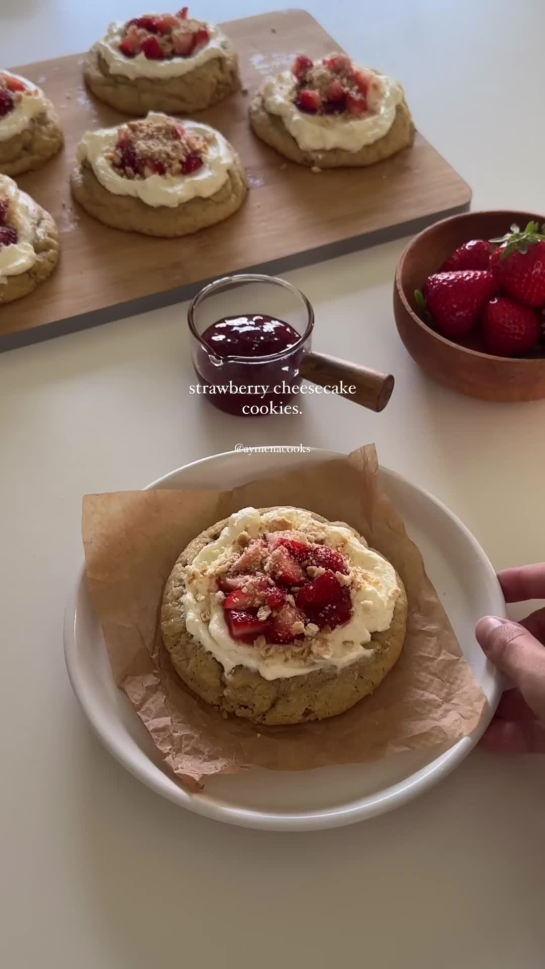 This may contain: strawberry shortcakes with cream cheese frosting and strawberries on the side are ready to be eaten