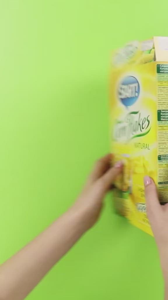 This may contain: someone is holding a carton of toilet paper in front of a lime green wall